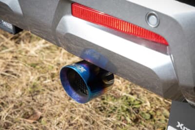 三菱 デリカミニ：ブルーテールチップを採用した専用マフラーカッター。純正のテールエンドにバンドで固定するだけで簡単に装着可能。デリカD:5と同様に、スポーティなイメージに仕上げられる