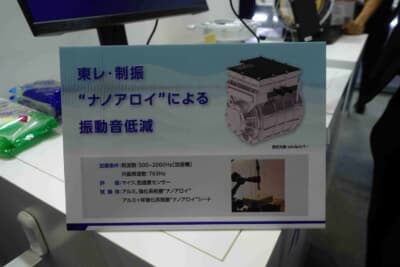 東レブース:ナノアロイによるeアクスルカバーの振動音低減効果を示す展示パネル。500〜2000Hzの加振条件での試験結果をアルミ単体と比較している