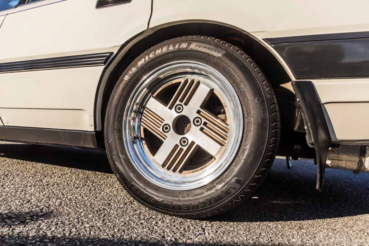 日産 レパード：4本スポークデザインの純正アルミホイールをクローズアップ。ミシュランの現代タイヤを組み合わせ、足元の実用性とオリジナルの雰囲気を両立させている