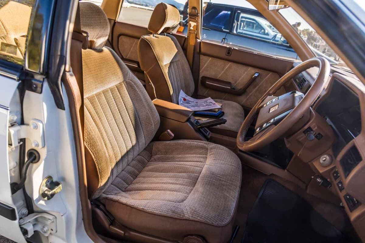 日産 レパード：助手席側から見た前席。起毛素材のブラウン系シートにヤレが少なく、長く倉庫で保管されてきた個体ならではのコンディションの良さが伝わる