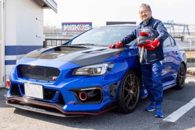 スバル WRX STI:サーキットのピットに佇む2018年式のWRブルー・パール。ヘルメットを手にしたオーナーの“青ちゃん”さんと相棒の一枚だ
