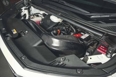 トヨタ ヴェルファイア：40系のエンジンルームに収まるブリッツ製カーボンダクト。純正然と馴染みつつT24A-FTSへ外気を導く要となる部分だ