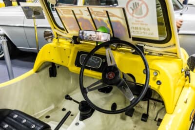 ダイハツ フェローバギィ：風防越しに見る運転席まわり。黒いステアリングと最小限の操作系、露出した白いFRPのフロアが簡素な成り立ちを物語る