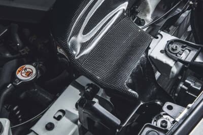 ブリッツ カーボンインテークシステム：ウェットカーボンの艶やかな織り目が映えるダクト。車種専用成形でエンジンルームへ隙なく収まる